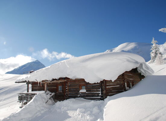 Alpine hut covered in deep snow on the Reiteralm